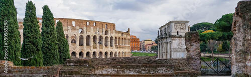 panoramic crop of ancient colosseum near historical buildings