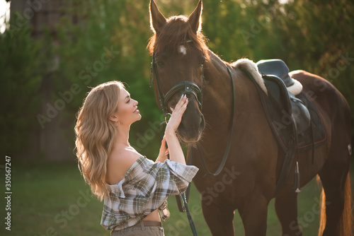 Portrait of girl inplaid shirt with black horse in the horse farm.