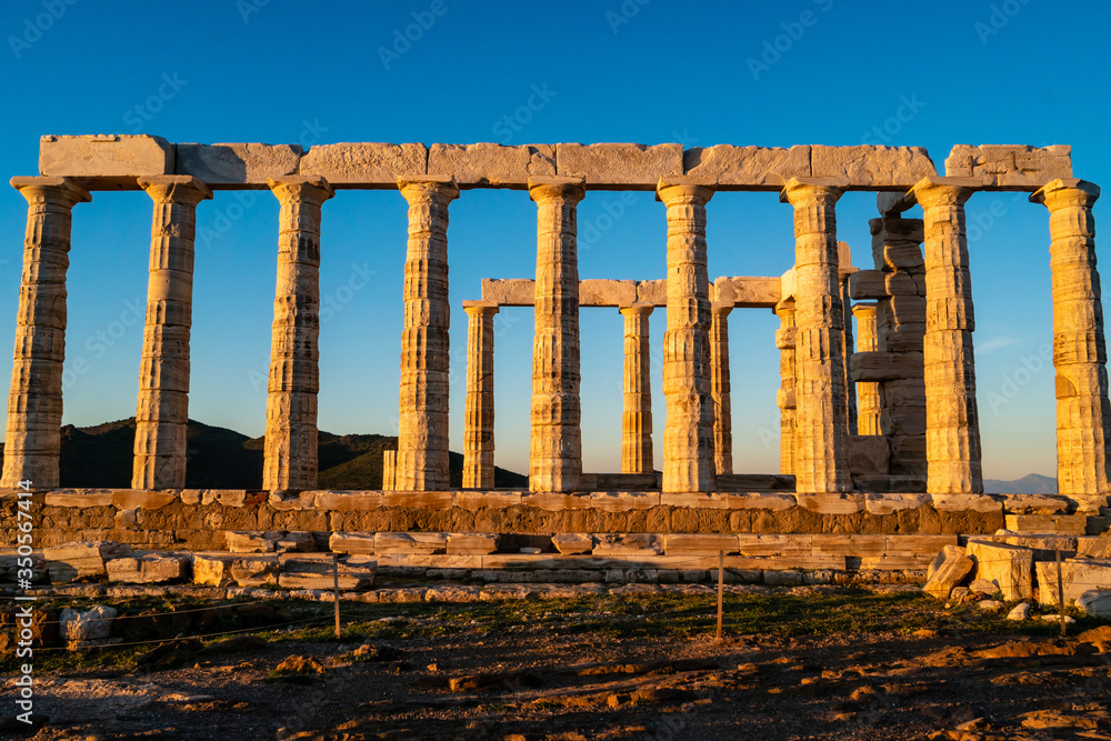 Fototapeta premium Sunshine on ancient columns of Parthenon in Athens against blue sky