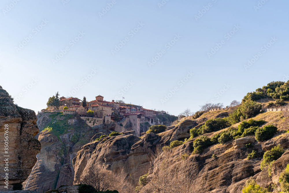 sunshine on rock formations with orthodox monastery in meteora