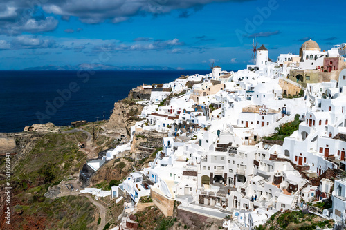 White houses near tranquil sea against sky with clouds in Santorini