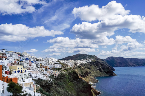 white houses near tranquil sea against blue sky with clouds in greece