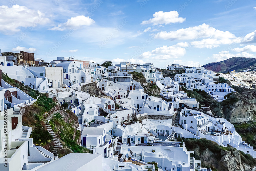 Fototapeta premium White houses on hill against sky with clouds in Greece