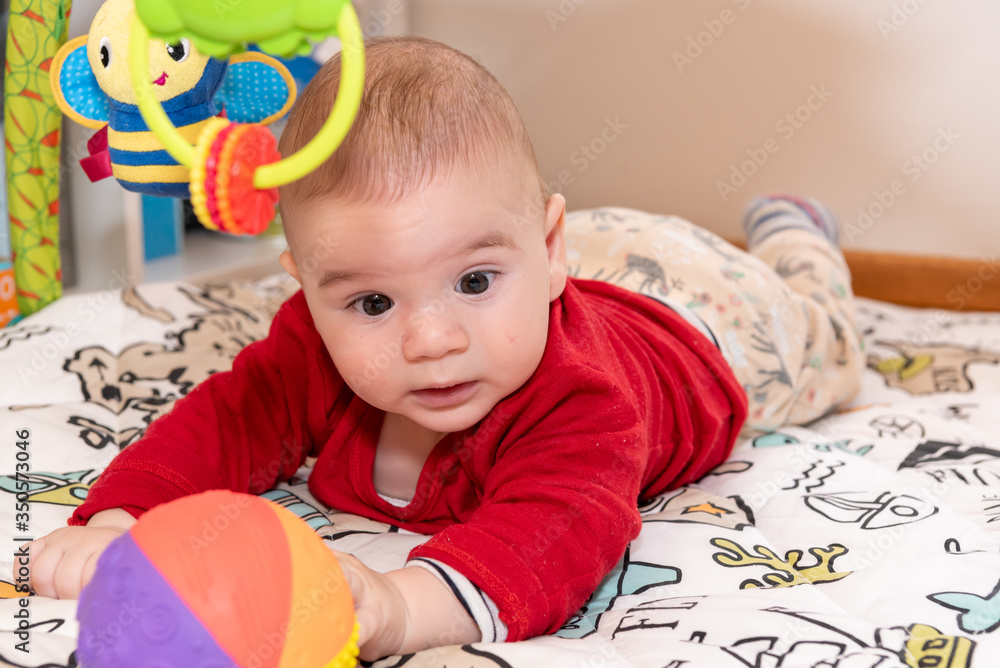 Adorable 6 months old little baby boy during tummy time surrounded by colourful toys Adorable 6 months old little baby boy during tummy time surrounded by colourful toys