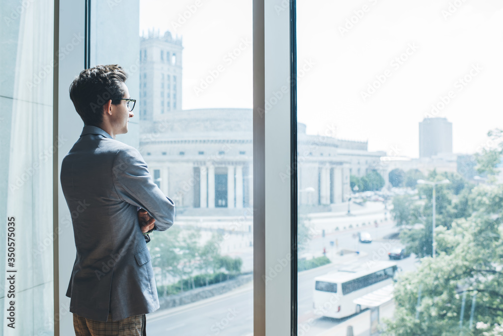 Serious businessman standing near window Serious businessman standing near window