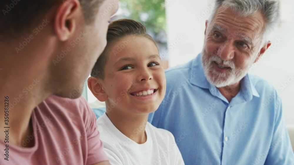 Multi-generation male hispanic family talking and laughing on sofa at home together - shot in slow motion Multi-generation male hispanic family talking and laughing on sofa at home together - shot in slow motion