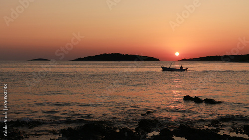 Single fisherman sailing out to the sea at sunset to catch fish on the open sea at Croatian side of Adriatic coast