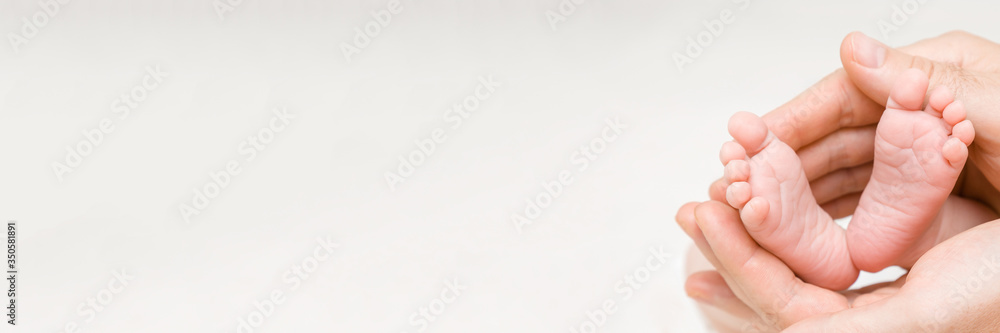 Newborn cute feet in young father hands. Lovely, emotional moment. Close up. Wide banner. Empty place for inspiration, sentimental text, quote on sayings or light gray background. Newborn cute feet in young father hands. Lovely, emotional moment. Close up. Wide banner. Empty place for inspiration, sentimental text, quote on sayings or light gray background.
