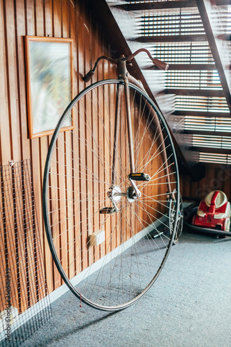 Old fashioned bicycle with one big and one small wheel under the stairs in a house. photo