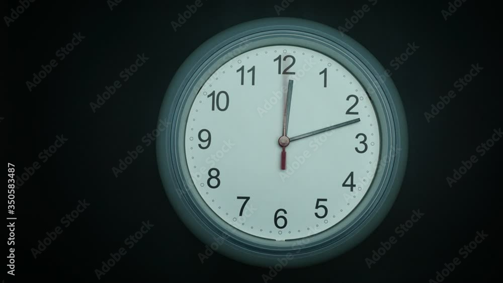 Close up Move the camera angle from right to left, Gray wall clock shows time 12 o'clock on black background, Time lapse 60 minutes moving fast, Time concept. Close up Move the camera angle from right to left, Gray wall clock shows time 12 o'clock on black background, Time lapse 60 minutes moving fast, Time concept.