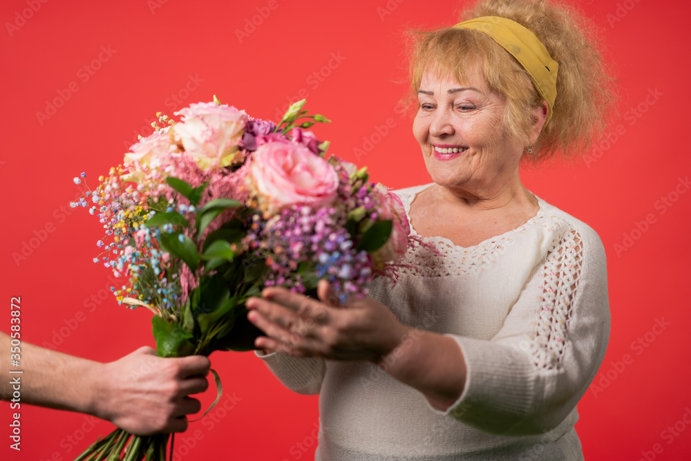 Naklejka premium hands of a young woman giving a bouquet of tulips to an elderly woman.march 8, mother's day concept