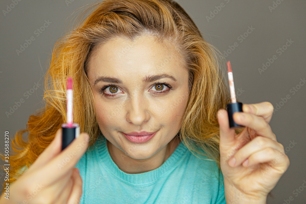 Obraz premium Beauty blogger is testing makeup. A young girl advises makeup.A girl is testing lip pencils and lipsticks. Beautiful woman paints her lips.