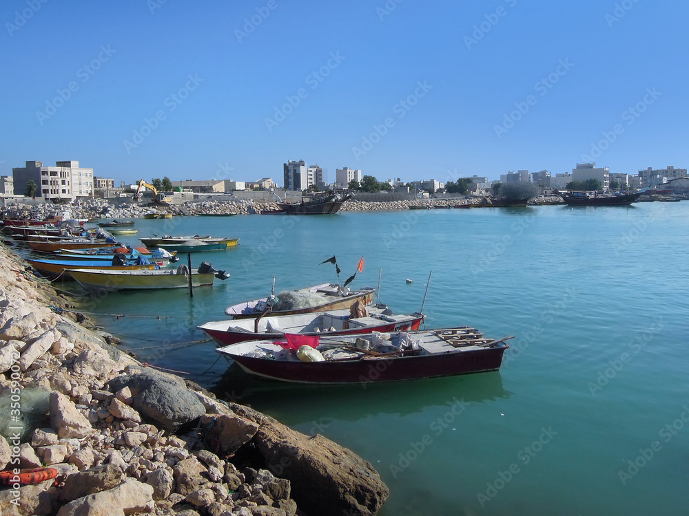 Sea boats near waterfront area in Bushehr, Persian Gulf, Iran. It's typical view for Persian sea port: both kind of boats, modern & traditional wooden (as seen on background), are popular at same time