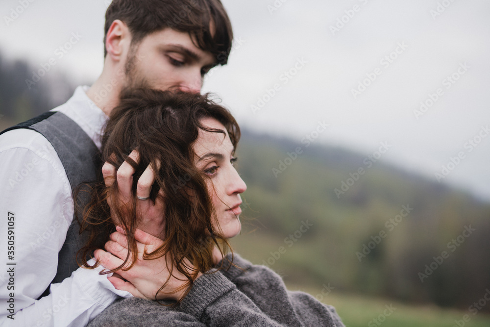 Romantic, young and happy caucasian couple in wedding clothes hugging on the background of beautiful mountains. Love, relationships, romance, happiness concept. Bride and groom traveling  together.