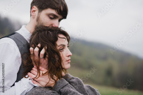 Romantic, young and happy caucasian couple in wedding clothes hugging on the background of beautiful mountains. Love, relationships, romance, happiness concept. Bride and groom traveling together.
