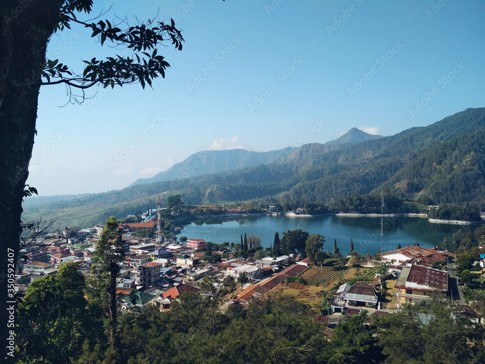 Small town by the lake on top of mountains. Morning view of a beautiful small town landscape from the top with clear blue sky