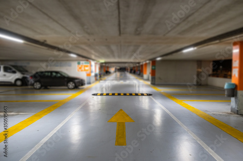 Yellow markings with blurred modern cars parked inside closed underground parking lot.