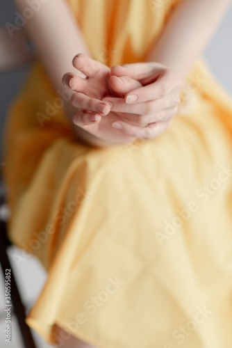 A young girl s thin hands. Girl in a yellow dress 