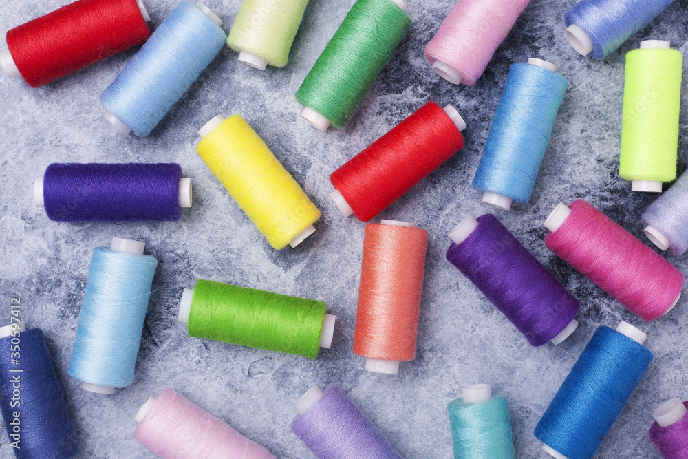 Colorful threads on bobbins, sewing set.On gray concrete background. Place for text. Colorful threads on bobbins, sewing set.On gray concrete background. Place for text.