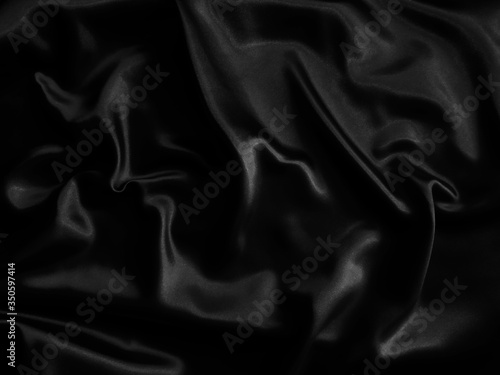 Black glossy crumpled fabric. Wavy fluid background