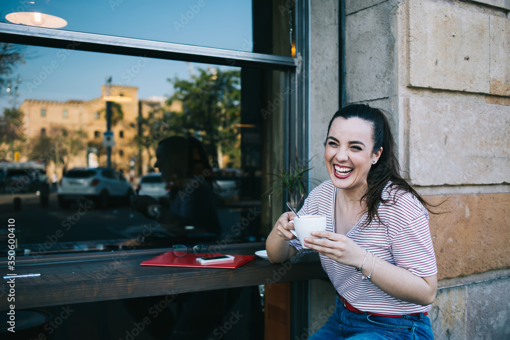 Happy emotional caucasian brunette 20s woman enjoying aroma coffee on breakfast in cafeteria on vacation holidays, cheerful young hipster girl laughing on joke holding espresso cup outdoors Happy emotional caucasian brunette 20s woman enjoying aroma coffee on breakfast in cafeteria on vacation holidays, cheerful young hipster girl laughing on joke holding espresso cup outdoors
