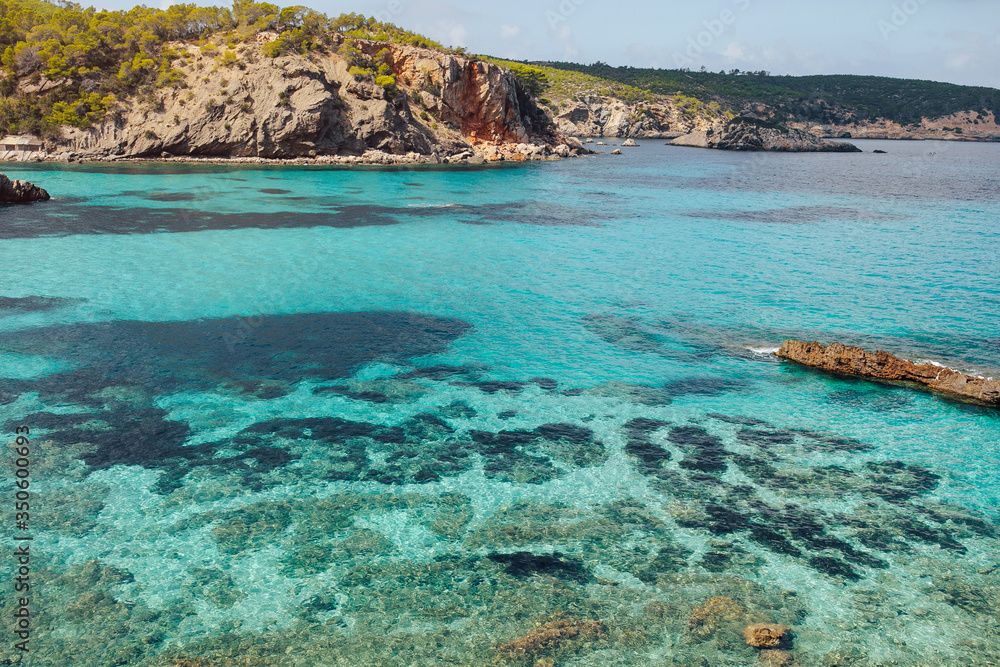 Beautiful view of Cala Portinax, Ibiza. Amazing sea view in sunny summer day from rocky coast.