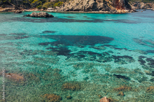 Beautiful view of Cala Portinax, Ibiza. Amazing sea view in sunny summer day from rocky coast.