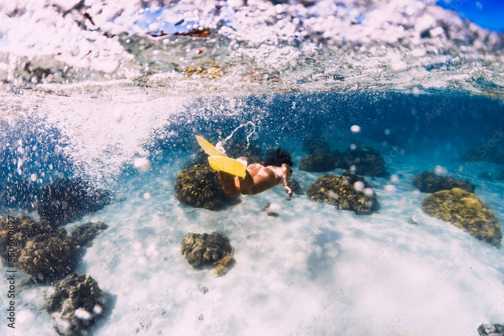 © artifirsov - Woman swimming underwater with yellow fins in ocean. Freediving or snorkeling in Mauritius