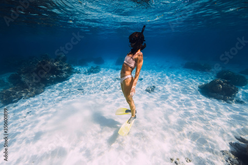 Woman swimming underwater with yellow fins in ocean. Freediving or snorkeling in Mauritius