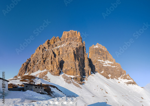 close up of wonderful snowy rocky mountain tre cime di lavaredo in dolomites in blue sky, italy. January 2020
