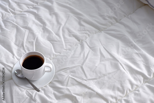 A Cup of black coffee on white bed linen. Suitable for advertising background. Minimalism.
