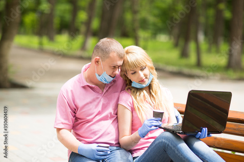 guy and girl are sitting in the park with a computer, 
coronavirus, covid