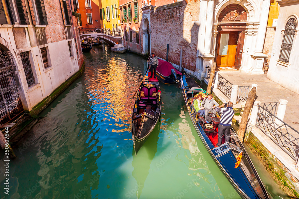 Typical canal with tourist gondolas in Venice in Veneto, Italy
