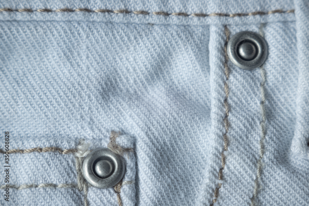 Macro texture with white and blue denim with rivets and a seam. Textile, fabric Macro texture with white and blue denim with rivets and a seam. Textile, fabric
