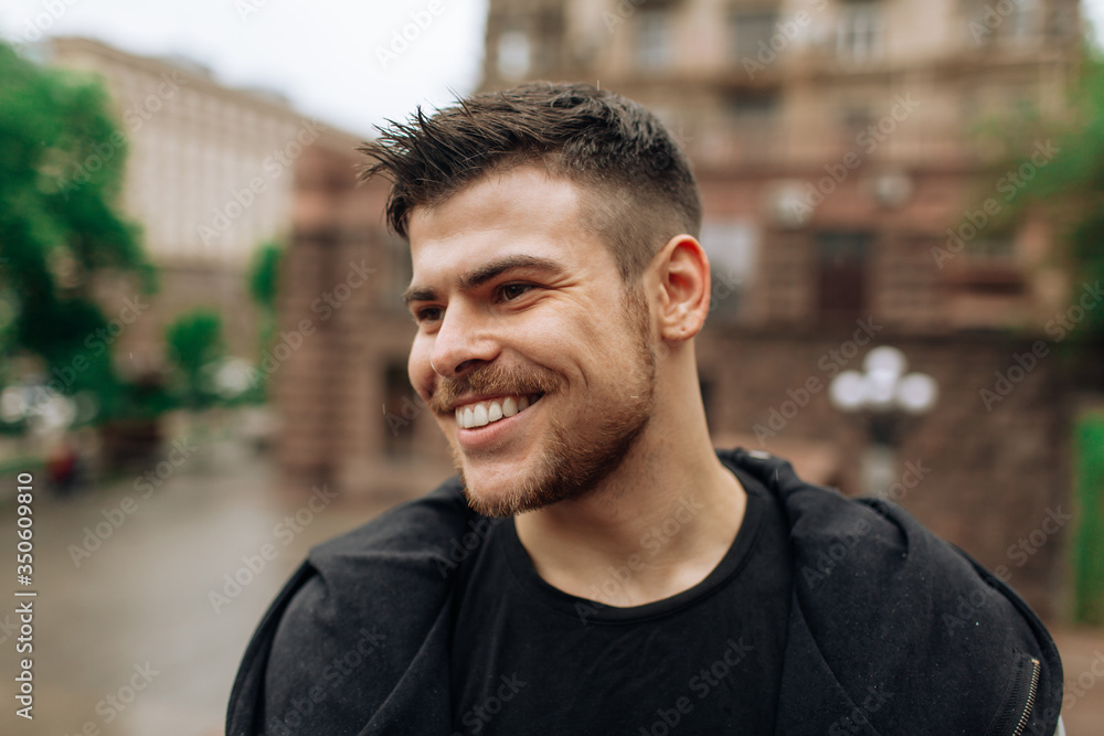 Portrait of a young man walking around the city. Brunette, beard. Cheerful, beautiful smile. Portrait of a young man walking around the city. Brunette, beard. Cheerful, beautiful smile.