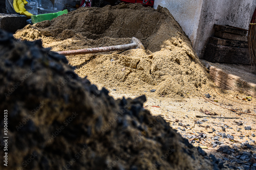 Fototapeta premium A hoe left on sand pile after labour working hard on house maintenance the whole sunny day