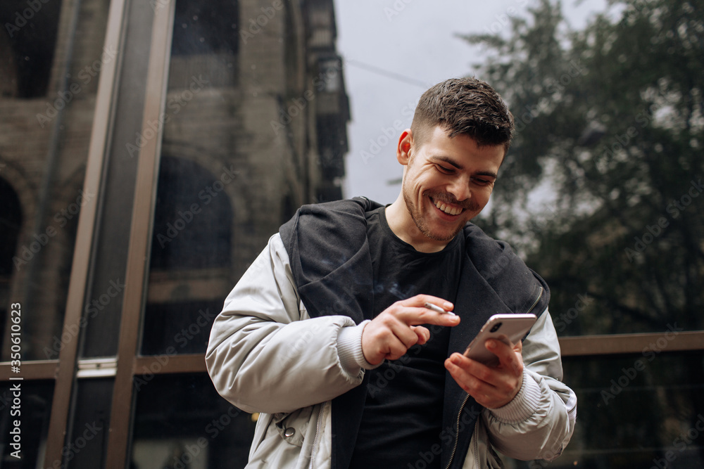 Portrait of happy young man walking on the street and looking aside while talking by his phone. Portrait of happy young man walking on the street and looking aside while talking by his phone.