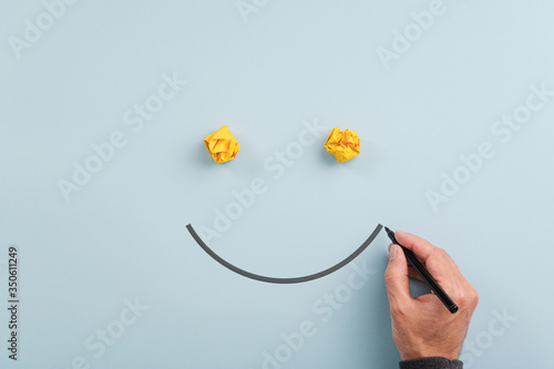 Male hand drawing a smiling face with black marker photo