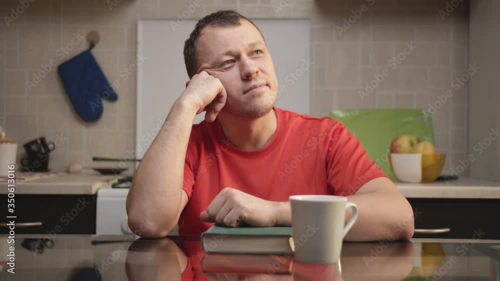 Young man dreams sitting at the kitchen table at home Young man dreams sitting at the kitchen table at home