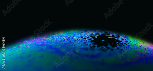 Fototapeta Naklejka Na Ścianę i Meble -  Rainbow soap bubble on black background. Strange colorful planet. 
