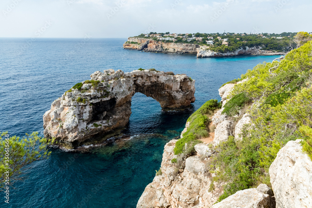 Es Spontás, imposing natural stone arch nestled in the sea near the coast. Santanyi, Mallorca Spain