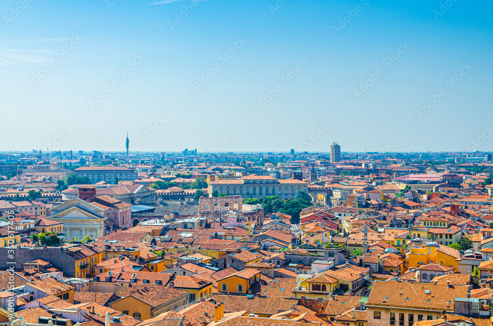 Fototapeta premium Aerial view of Verona city historical centre Citta Antica with red tiled roof buildings. Panoramic view of cityscape of Verona town. Blue sky background copy space. Veneto Region, Northern Italy