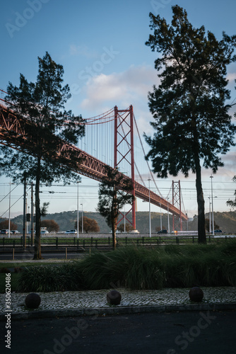 Fototapeta Naklejka Na Ścianę i Meble -  view of the 25 de abril bridge in lisbon from the shore framed by trees