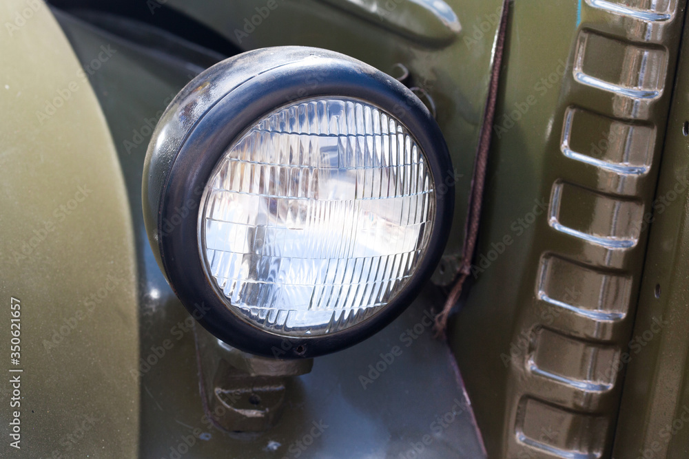 Old style dark green truck lamp. Vintage automobile front side. Closeup. soft focus.