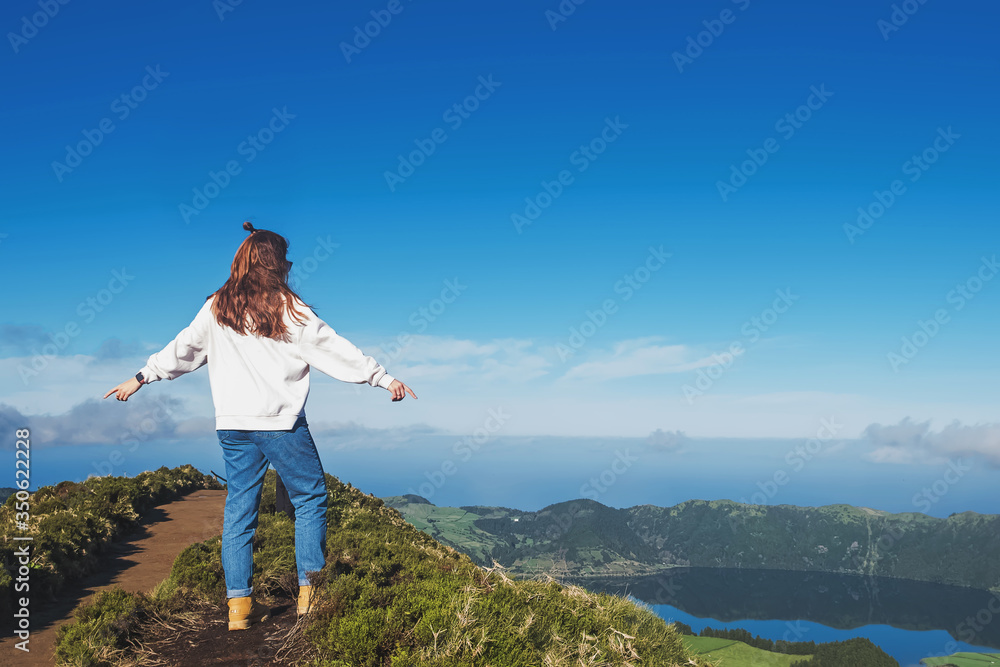 Naklejka premium Young woman tourist standing with the view to the mountain lake