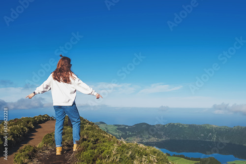 Young woman tourist standing with the view to the mountain lake