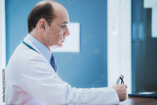 Medical Doctor Sitting At Desk In Office.