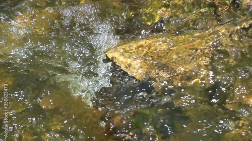 river water flowing over stones slow motion x10 photo