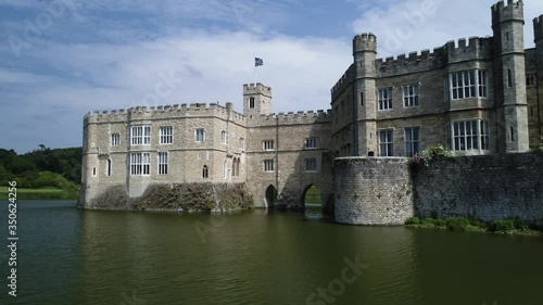 Flag blows in wind atop impressive castle with moat in sunshine photo