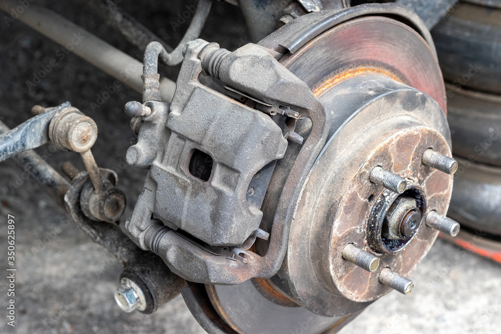Rusty back car wheel hub with brake disc at tire shop. Car without a wheel while replacing on the tire service center. Closeup side view. Selective focus Rusty back car wheel hub with brake disc at tire shop. Car without a wheel while replacing on the tire service center. Closeup side view. Selective focus